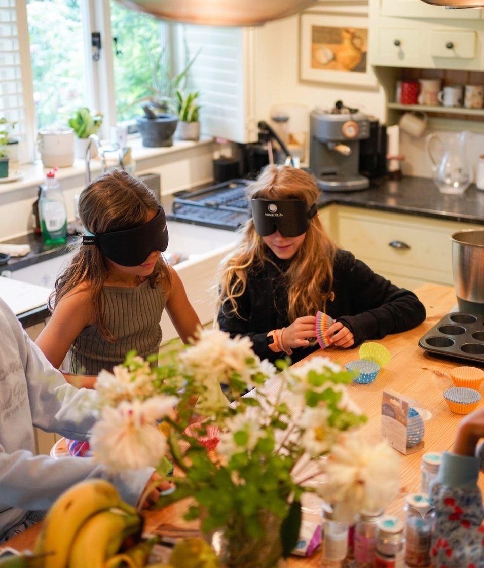 Two blindfolded girls reading cards at the kitchen table