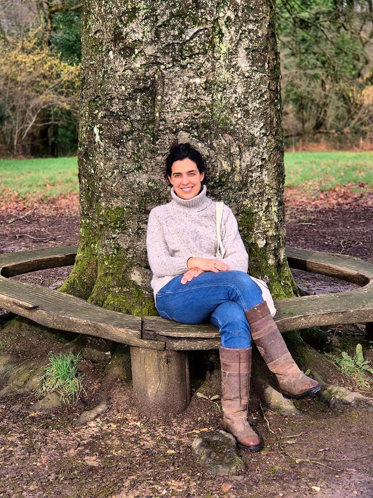 Paula McMeekin sitting on a circular bench around a large tree in a park